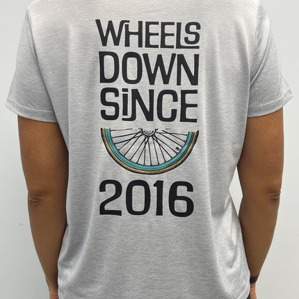 Person wearing a white t-shirt with 'Wheels Down Since 2016' text and bicycle graphic.