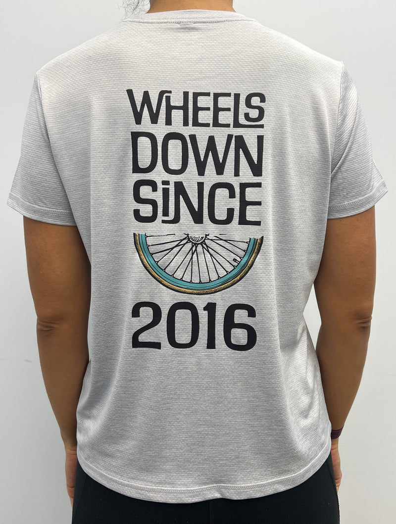 Person wearing a white t-shirt with 'Wheels Down Since 2016' text and bicycle graphic.