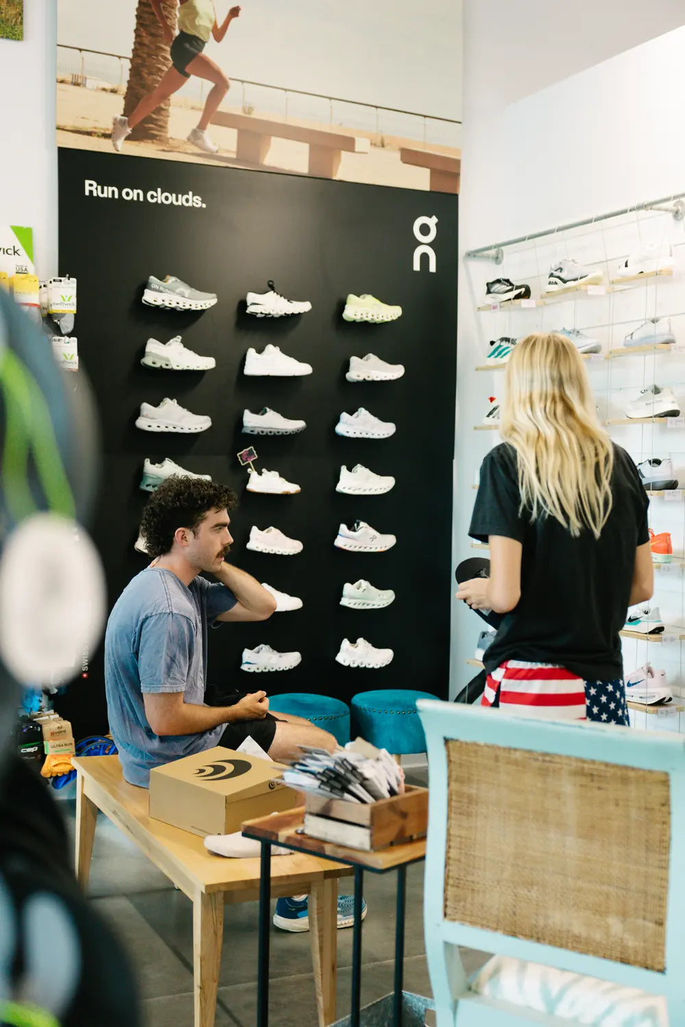 Customers trying on running shoes in front of the On shoe wall